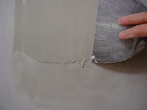 photo applying a second coat of joint compound over paint bubbles
